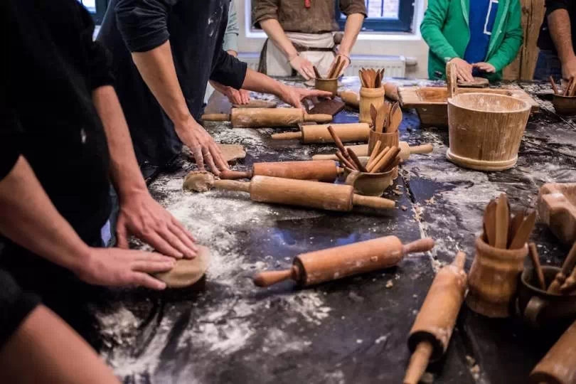Grupa osób, która odwiedza Muzeum Piernika w Toruniu i bierze udział w warsztatach z robienia pierników.