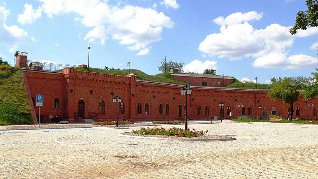 Rozległy i niski budynek z czerwonej cegły, który należy do Muzeum Twierdzy Toruń.